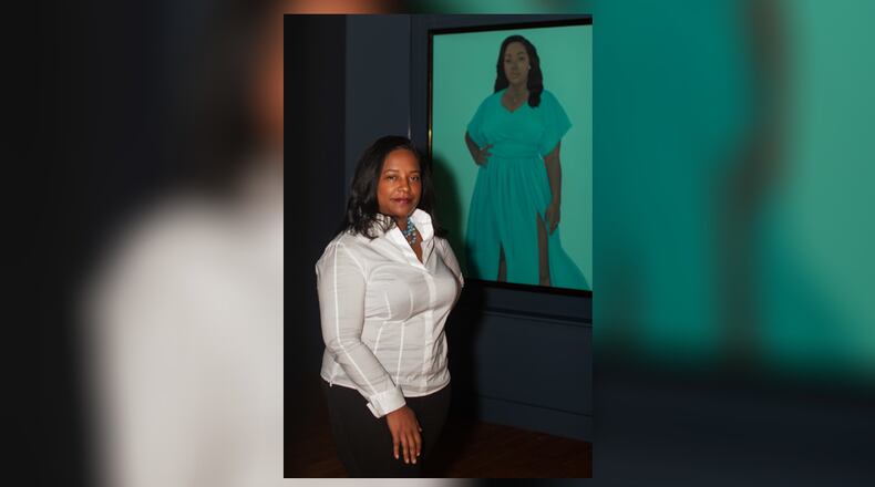 Tuliza Fleming stands in front of a portrait of Breonna Taylor, the Black woman shot and killed by Louisville police officers in 202. The portrait is by Amy Sherald, the artist who painted the official portrait of First Lady Michelle Obama. Fleming, who grew up in Yellow Springs, is a curator at the Smithsonian's National Museum of African American History and Culture. PHOTO/NATIONAL MUSEUM OF AFRICAN HISTORY AND CULTURE
