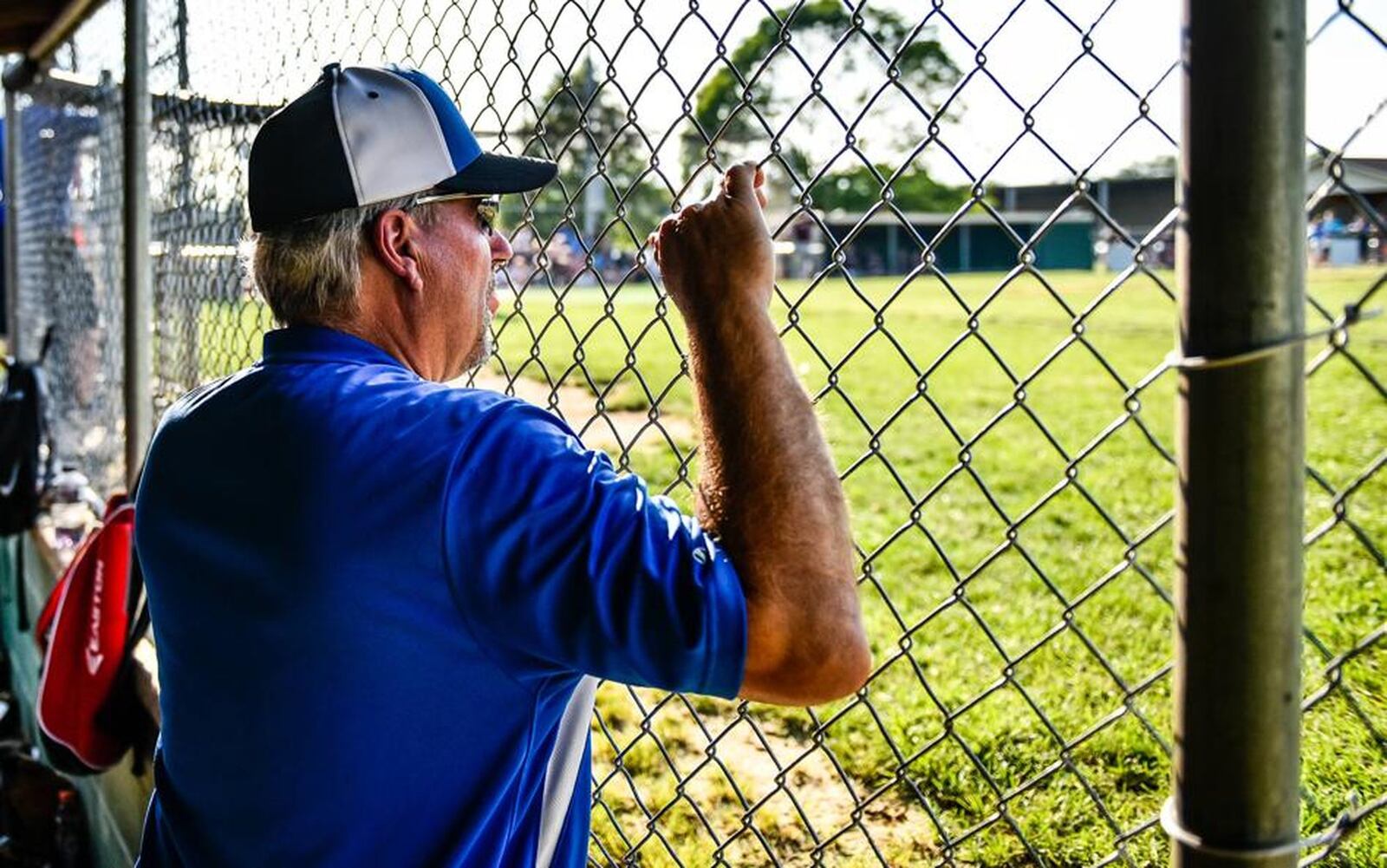 Hamilton West Side Little League assistant coach Tim Nichting watches from the dugout during the District 9 tournament final against Lebanon on July 10 at the West Side complex in Hamilton. NICK GRAHAM/STAFF