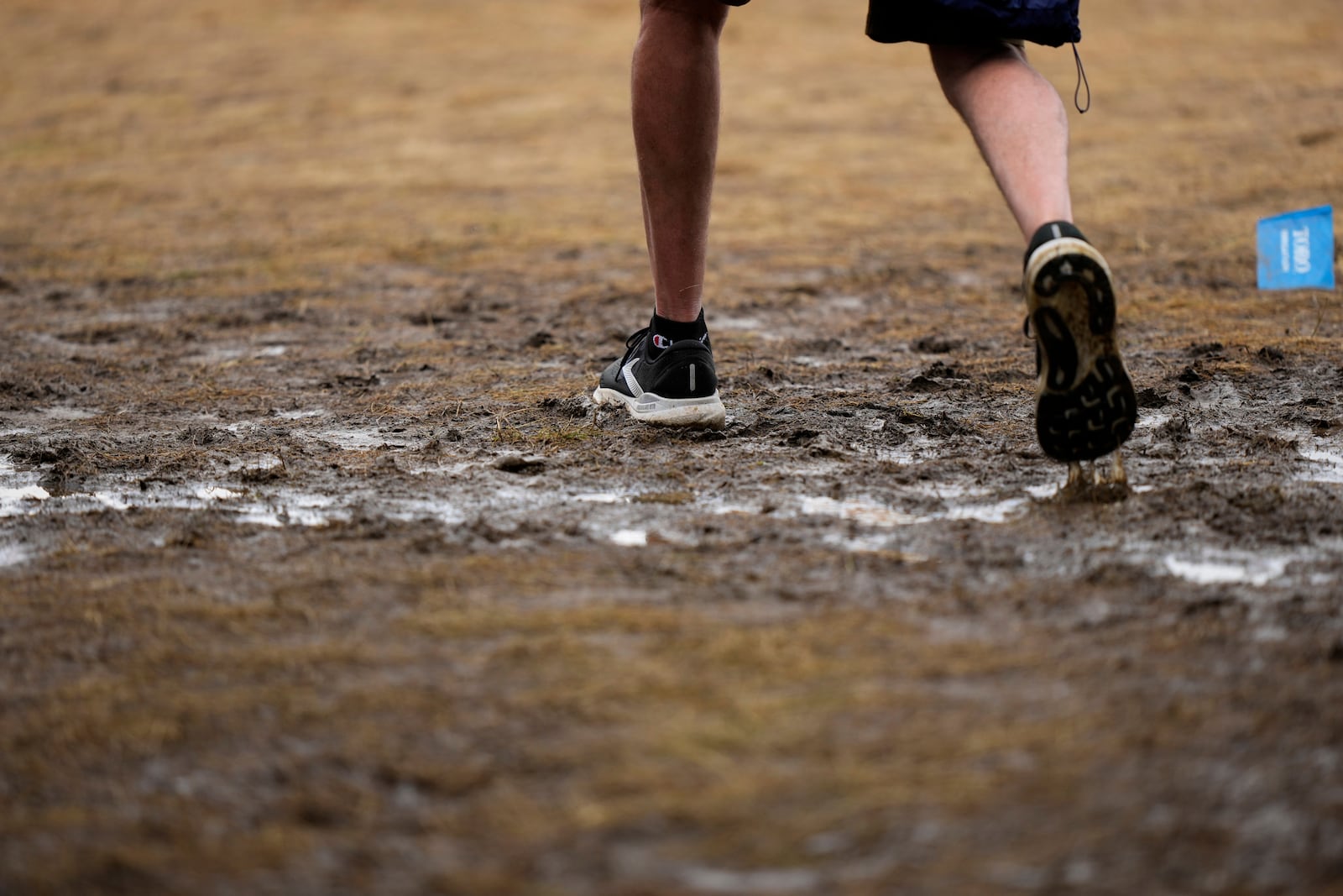 A fan walks through a soggy puddle near the 14th hole during the third round of the U.S. Open golf tournament at Oakmont Country Club Saturday, June 14, 2025, in Oakmont, Pa. (AP Photo/Charlie Riedel)