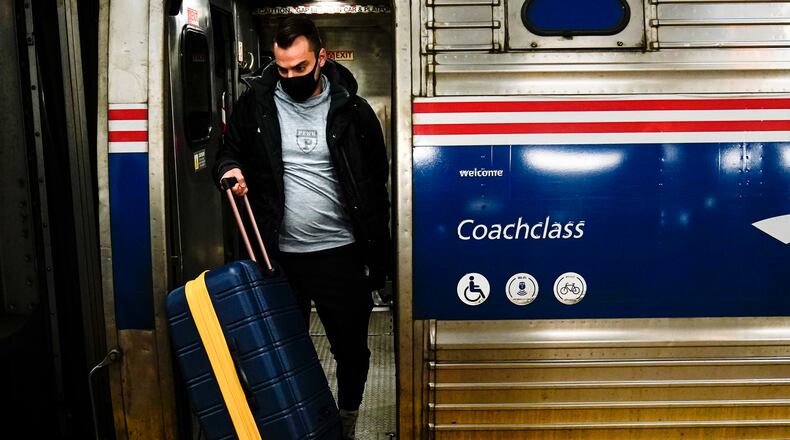 FILE - A traveler exits an Amtrak train ahead of the Thanksgiving Day holiday at 30th Street Station in Philadelphia, Wednesday, Nov. 24, 2021.  Amtrak will need to reduce service in January unless more employees get vaccinated against COVID-19, the passenger rail system’s president says. Stephen Gardner says about 95% of Amtrak workers are at least partially vaccinated. The rest face a Jan. 4 deadline that the Biden administration set for employees of federal contractors. (AP Photo/Matt Rourke, File)