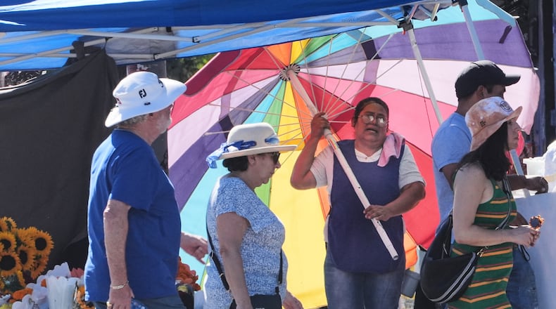 A street vendor uses an umbrella to shelter from the sun on a unseasonably hot day Tuesday, Oct. 28, 2025, in Los Angeles. (AP Photo/Damian Dovarganes)