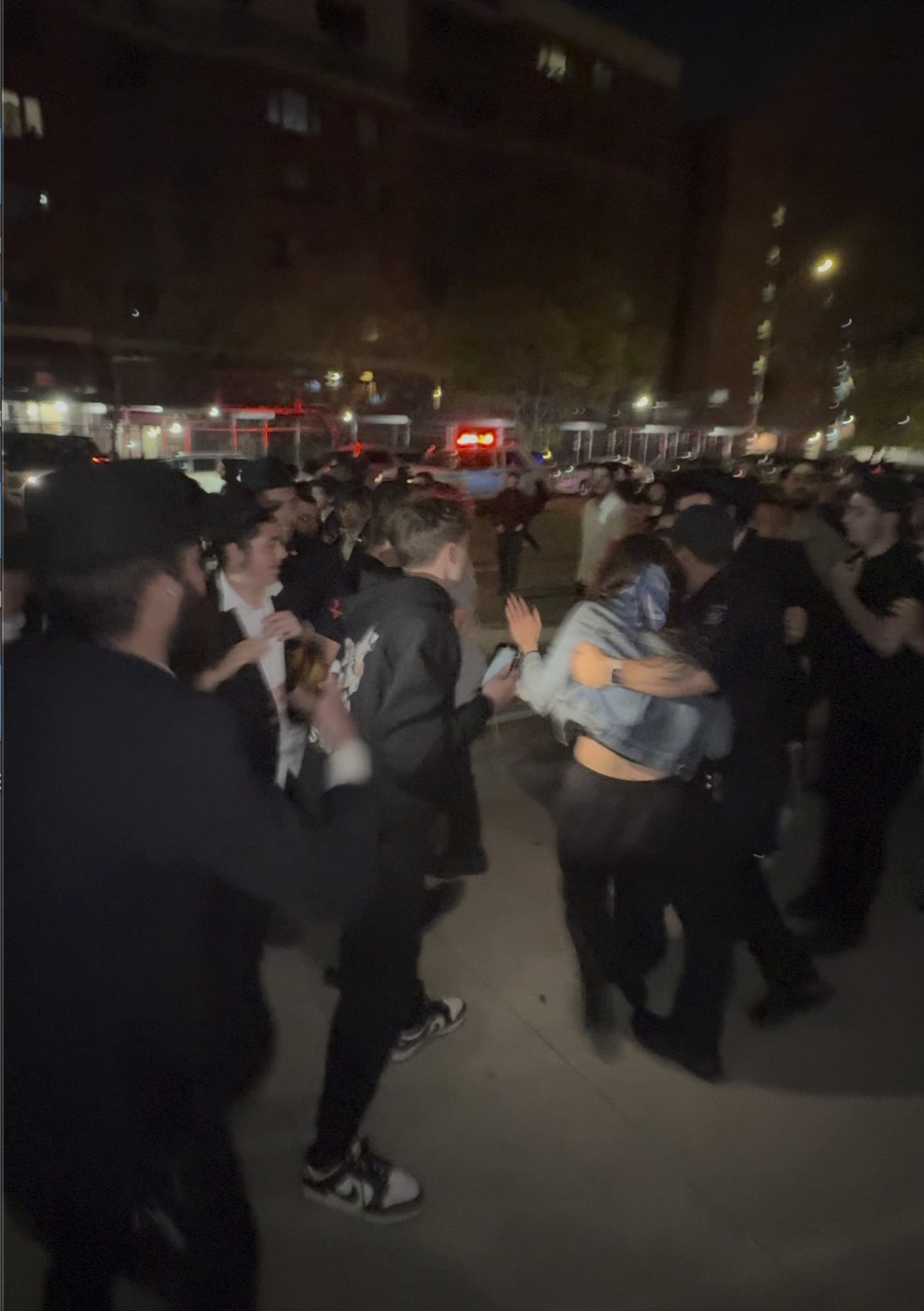 This image taken from video shows a woman and a police officer as they are pursued by a crowd of men in the Crown Heights section of Brooklyn, N.Y., on Thursday, April 24, 2025. (AP Photo)