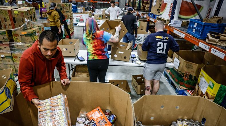 Foodbank Inc. volunteer Josh Ortiz, left box-up food for area senior at the warehouse Thursday November 7, 2024. JIM NOELKER/STAFF