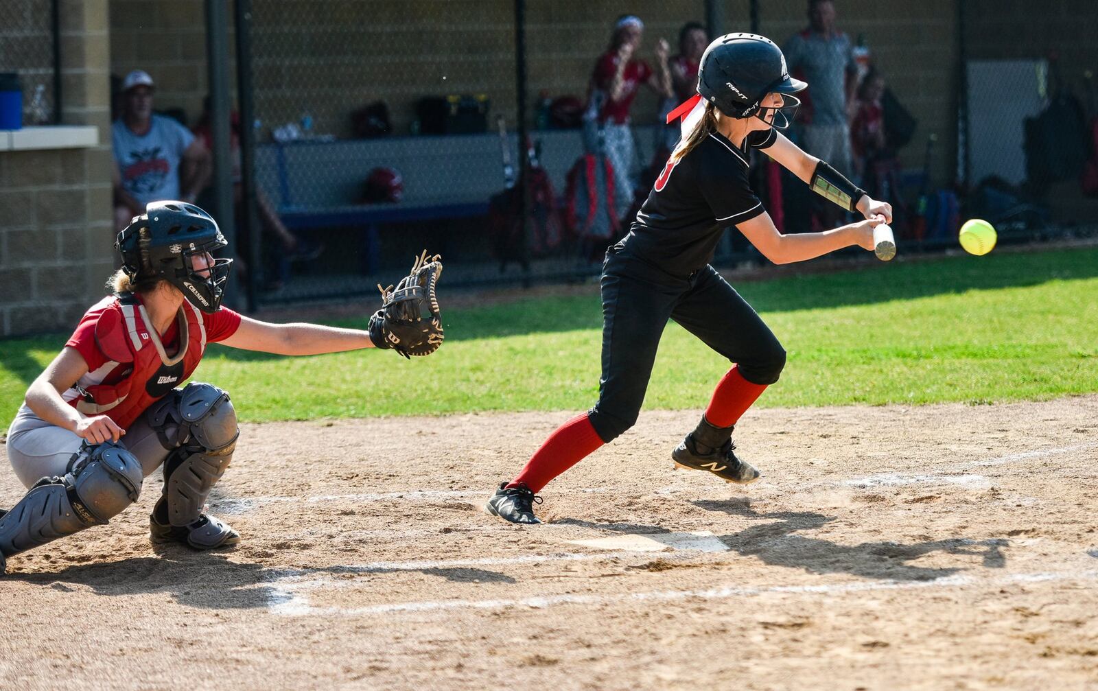 Madison’s Regan Dorman bunts the ball in front of Carlisle catcher Bailey Naylor on May 14 during a Division III district final at Lefferson Park in Middletown. NICK GRAHAM/STAFF