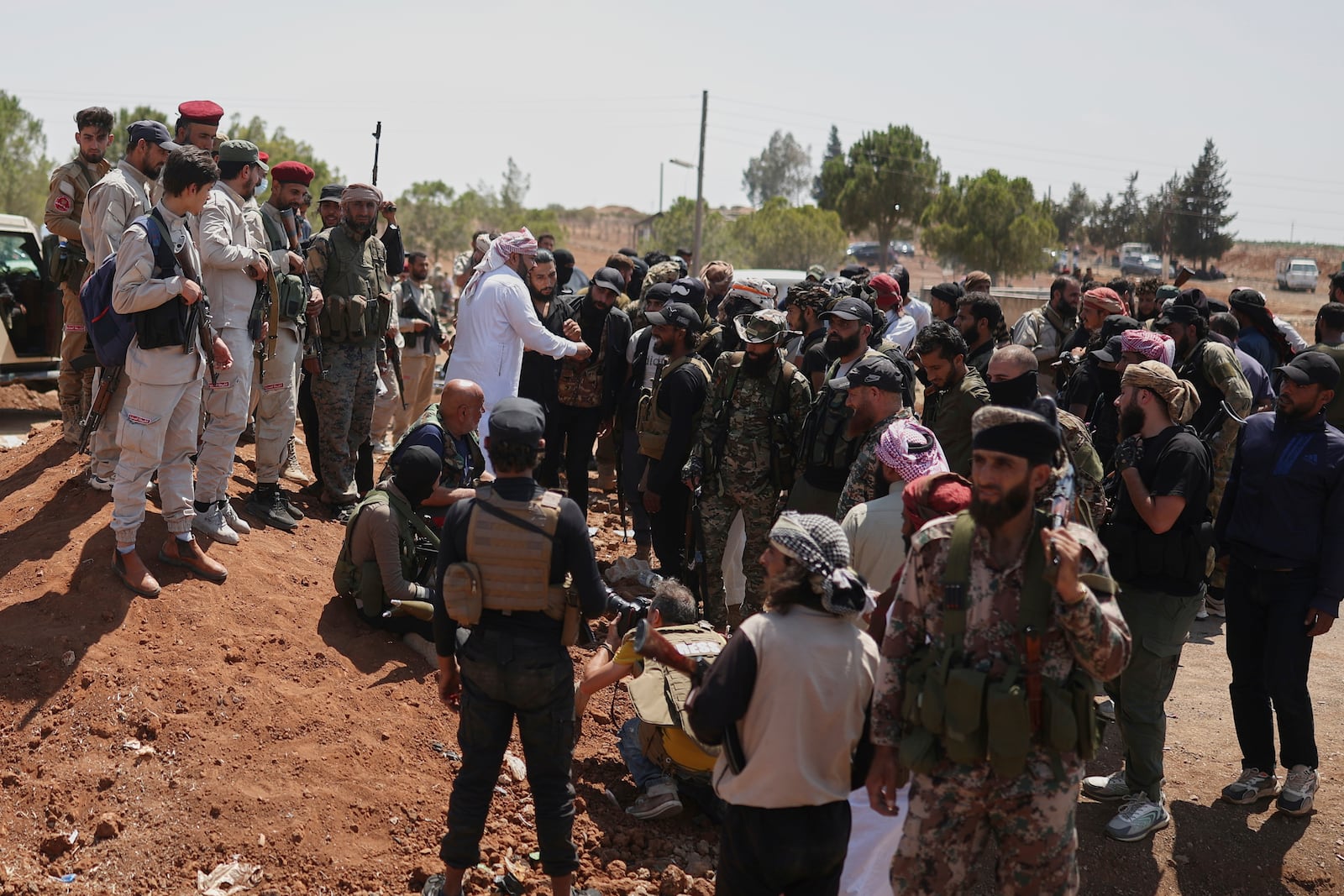 Bedouin fighters, right, gather as Syrian government security forces, left, block them from entering Sweida province, in Busra al-Harir village, southern Syria, Sunday, July 20, 2025. (AP Photo/Ghaith Alsayed)