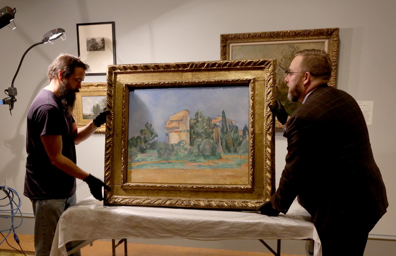 Paul Cezanne's "The Pigeon Tower at Bellevue" went on loan to the Dayton Art Institute from the Cleveland Museum of Art in October 2015. The DAI's preparator Erich Reith (left) and Per Knutas, chief conservator for the Cleveland Museum of Art, unpack and prepare to hang the painting. Painted between 1888 and 1892 the piece depicts a towering rock formation in the town of Bellevue in southern France where the artists brother-in-law lived. LISA POWELL / STAFF
