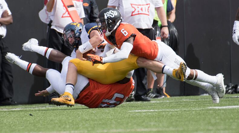 STILLWATER, OK - OCTOBER 29: Linebacker Devante Averette #40 and cornerback Ashton Lampkin #6 of the Oklahoma State Cowboys tackle quarterback Skyler Howard #3 of the West Virginia Mountaineers during the first half of a NCAA football game at Boone Pickens Stadium October 29, 2016 in Stillwater, Oklahoma. (Photo by J Pat Carter/Getty Images)