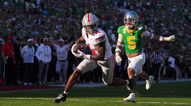 Ohio State wide receiver Jeremiah Smith (4) scores a touchdown against Oregon defensive back Kobe Savage (5) during the first half in the quarterfinals of the Rose Bowl College Football Playoff, Wednesday, Jan. 1, 2025, in Pasadena, Calif. (AP Photo/Mark J. Terrill)