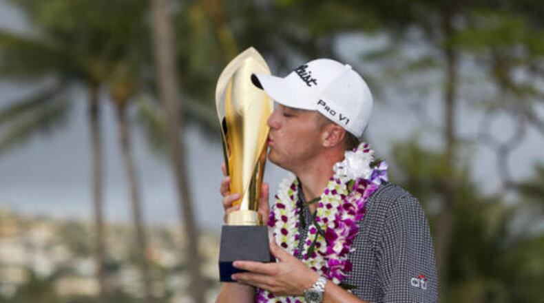 Justin Thomas kisses the trophy after winning the Sony Open golf tournament Sunday, Jan. 15, 2017, in Honolulu. Challenged only by the record book, Thomas won the Sony Open on Sunday with the lowest 72-hole score in PGA Tour history. (AP Photo/Marco Garcia)