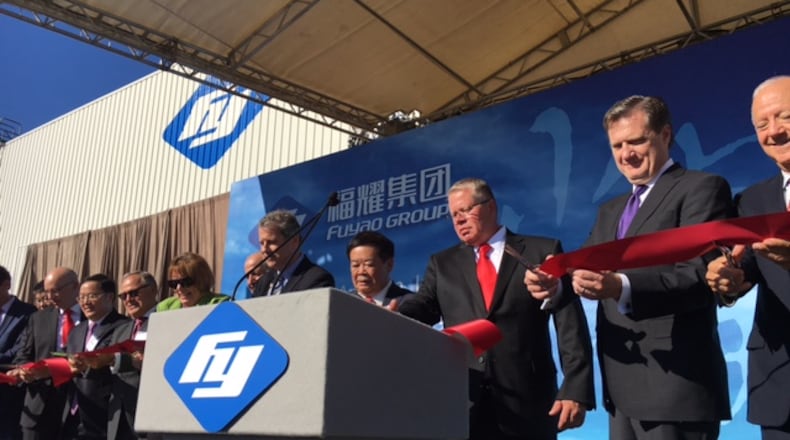 Joined by U.S. Sen. Sherrod Brown to his right, and Fuyao Glass America supervisor Michael Fullenkamp to his left, Fuyao Global Chairman Cho Tak Wong helped cut the ribbon at Fuyao’s Moraine plant in October 2016 at the company’s grand opening celebration. THOMAS GNAU/STAFF