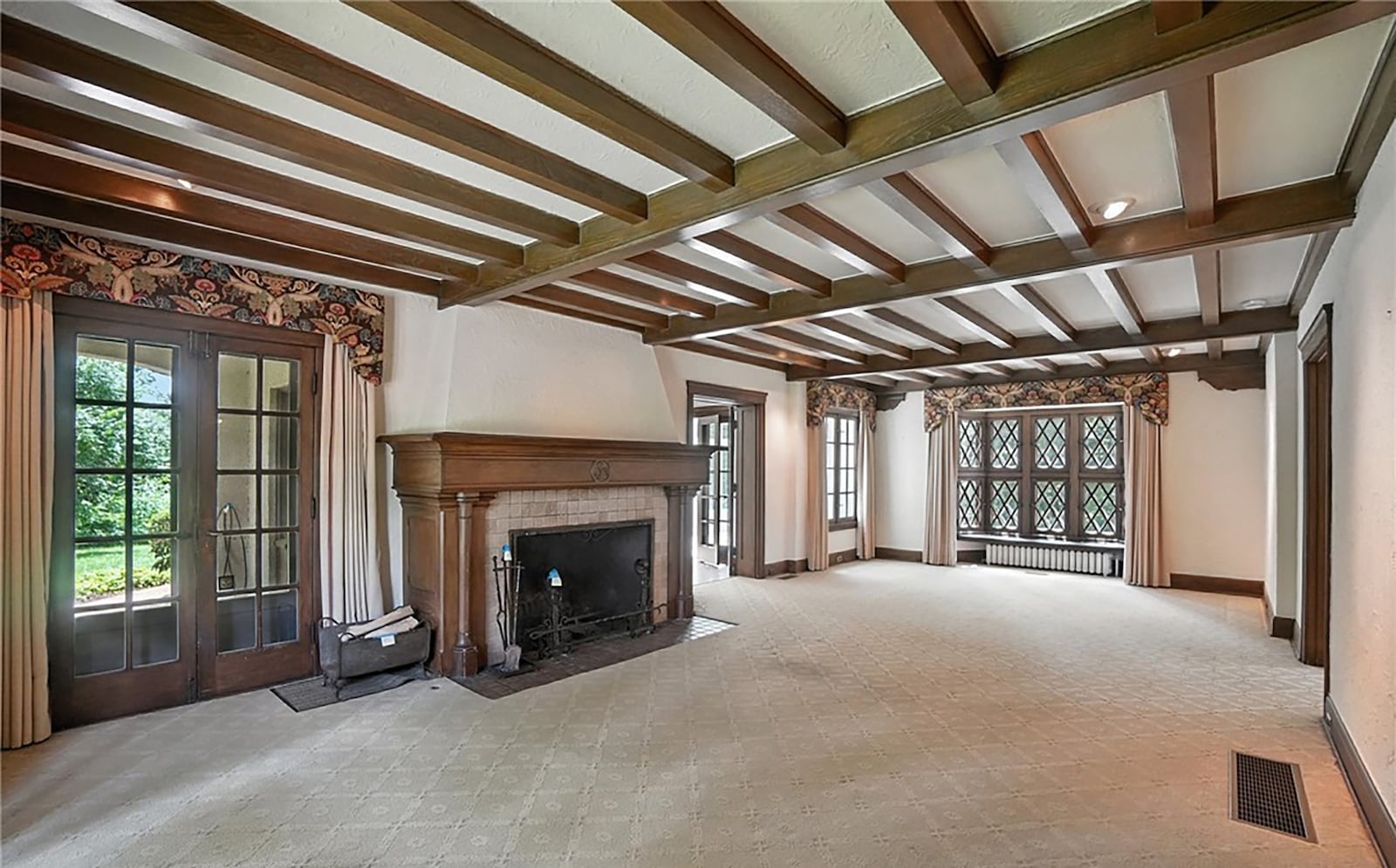 The formal living room has a beamed ceiling, recessed lighting and a woodburning fireplace.