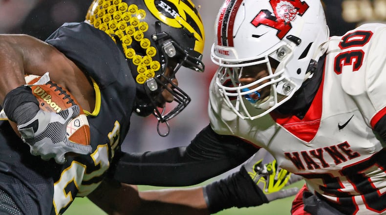 Centerville's Ziere Alston tries to avoid a tackle by Wayne's Marvin Williams during Friday's regional championship game. BILL LACKEY/STAFF