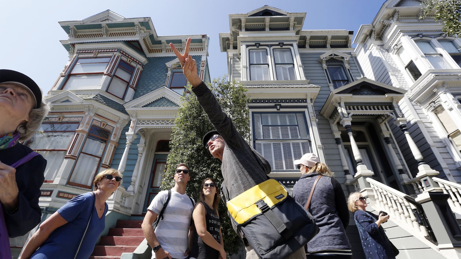 Participants of the Victorian Home Walk tour pause in front of a group of "painted ladies" victorian homes as host Jay Gifford, center, points out other types of building in the lower Pacific Heights neighborhood in San Francisco, Calif., on Friday, Sept. 15, 2017. Airbnb's new "experiences" feature allows people to use the platform to plan experiences as well as places to stay. (Laura A. Oda/Bay Area News Group/TNS)