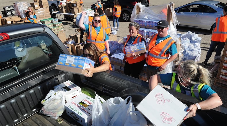 Volunteers load food into the back of a pickup truck Thursday, Sept. 9, 2021, during the Dayton Food Bank mass food distribution at the Wright State University Nutter Center. MARSHALL GORBY\STAFF