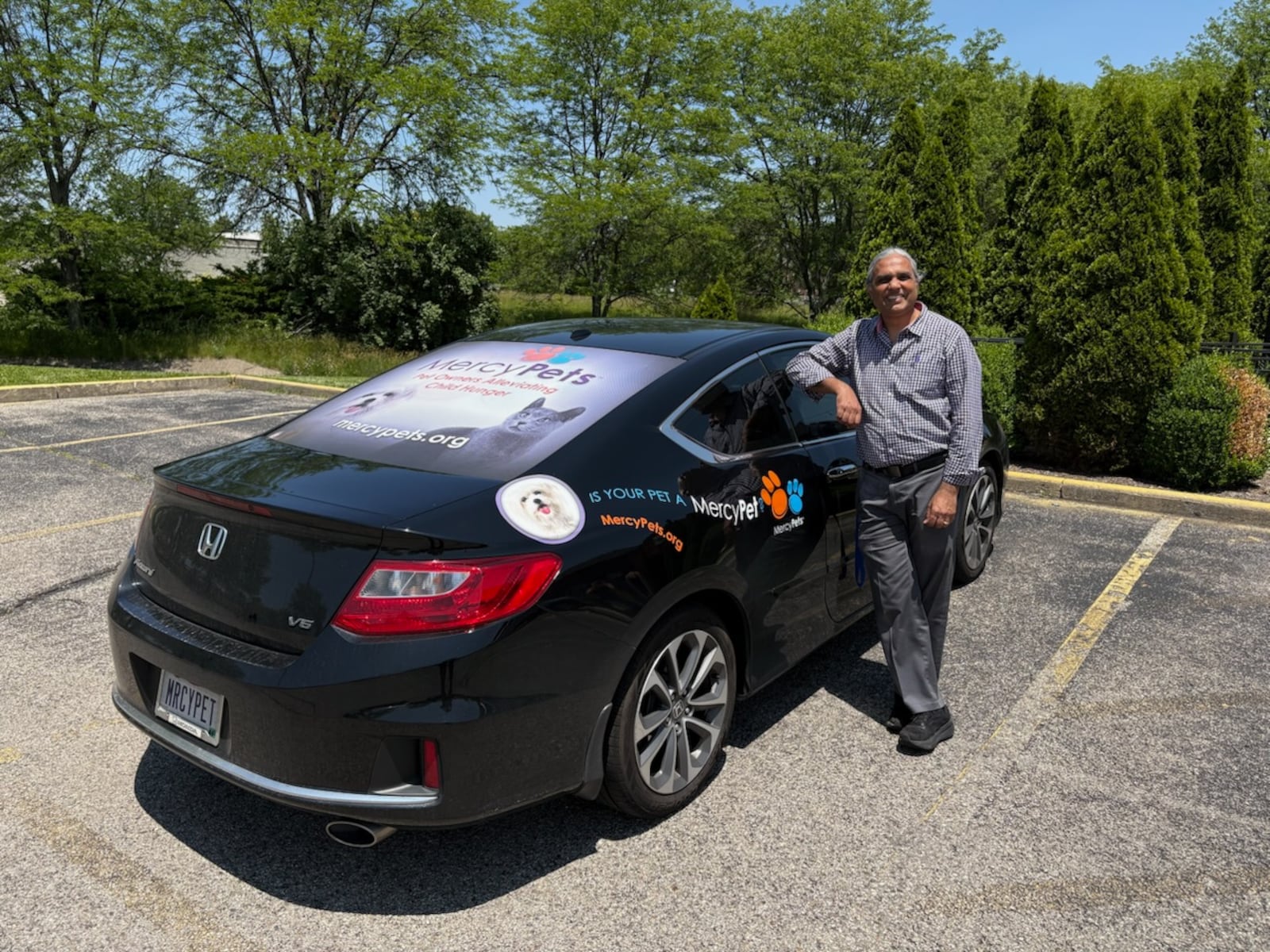 Father Satish Joseph with his car which promotes the MercyPets charity on the side panel back sun screen. CONTRIBUTED BY TOM ARCHDEACON