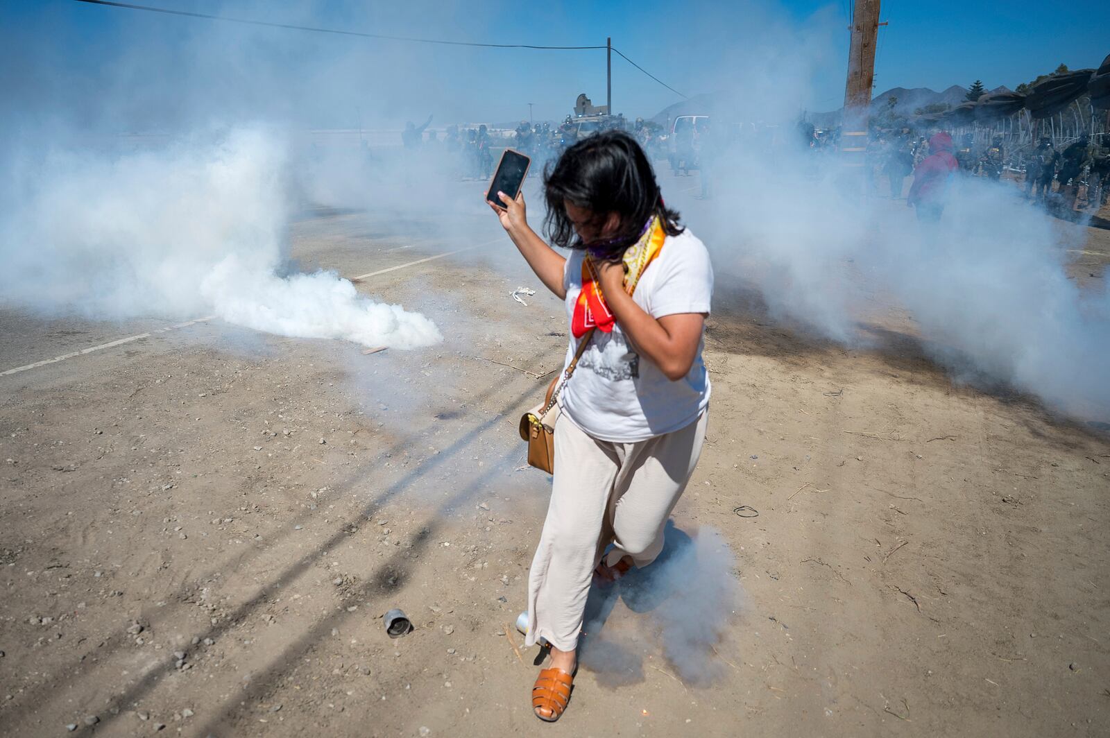 FILE - A protester runs from tear gas tossed by federal immigration agents to clear a path for the vehicles during a raid in the agriculture area of Camarillo, Calif., Thursday, July 10, 2025. (AP Photo/Michael Owen Baker, File)