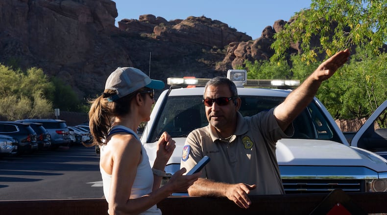 City of Phoenix Park Ranger Sam Weller, right, directs a hiker away from a trailhead closed due to extreme heat at Camelback Mountain on Thursday, March 19, 2026, in Phoenix. (AP Photo/Rebecca Noble)