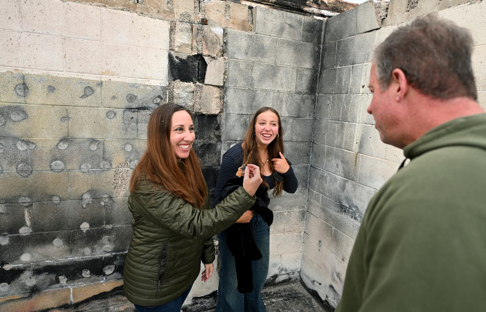Rachel McNett, left, finds a piece of her old passport as daughter Teagan and husband Keith look on as they visit there house that burned in the Mountain Fire Wednesday, April 16, 2025, in Camarillo, Calif. (AP Photo/Wally Skalij)