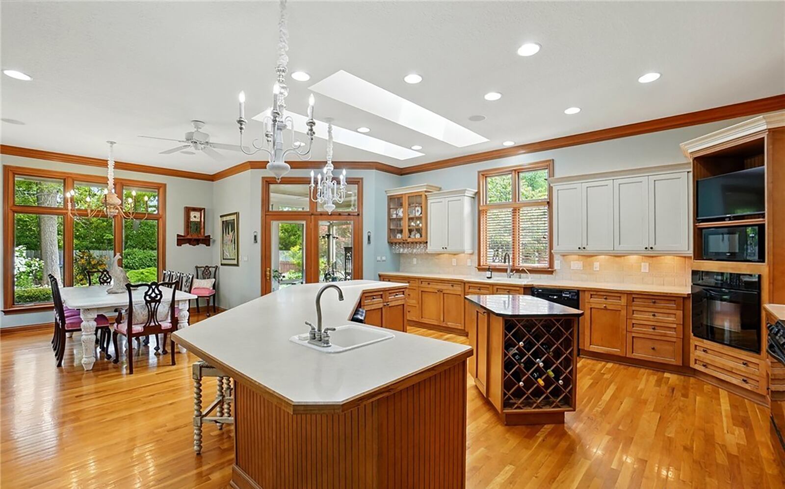 The open concept kitchen has wood flooring, skylights, recessed lighting and two islands - one with seating. It is open to the dining room.