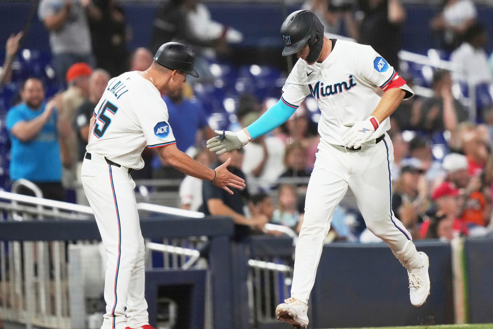 Miami Marlins' Eric Wagaman, right, greets the third base coach after hitting a solo home run during the fifth inning of a baseball game against the Cincinnati Reds, Monday, April 21, 2025, in Miami. (AP Photo/Lynne Sladky)