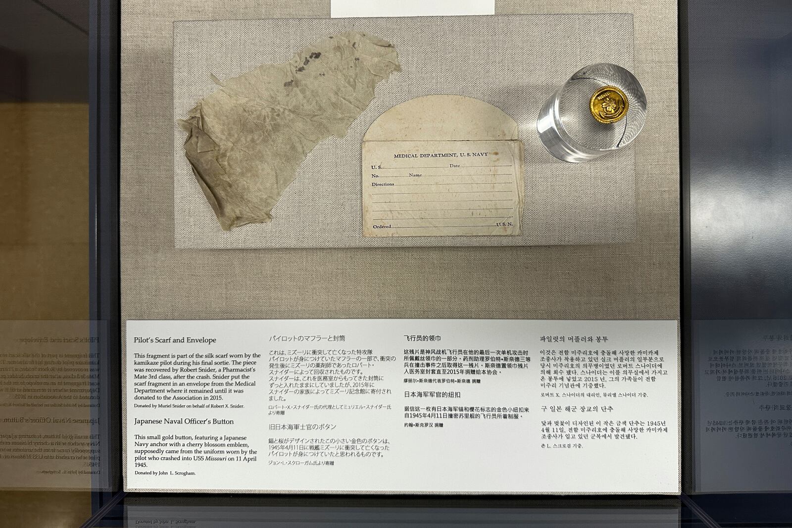 A fragment of a silk scarf and a button worn by the kamikaze pilot of a Japanese zero plane that rammed into the USS Missouri during the Battle of Okinawa is on display at the Battleship Missouri Memorial in Pearl Harbor on April 3, 2025. (AP Photo/Audrey McAvoy)