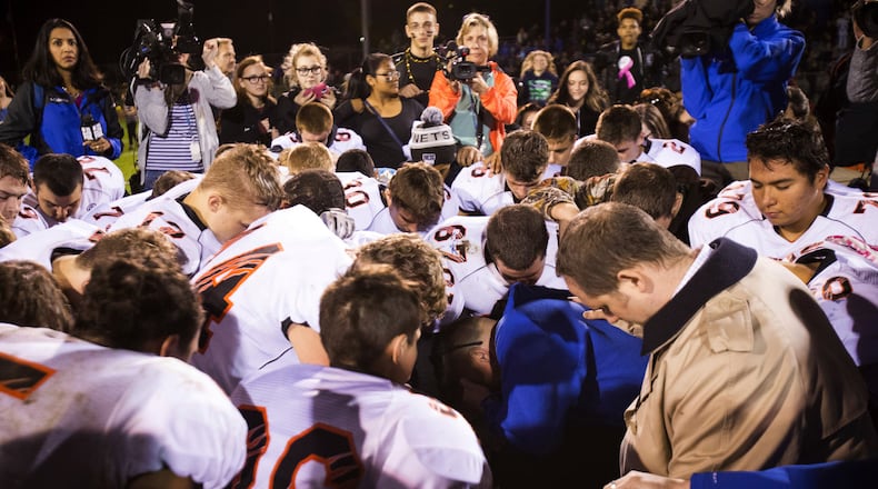FILE - Bremerton High School assistant football coach Joe Kennedy, center in blue, kneels and prays after his team lost to Centralia in Bremerton, Wash., Oct. 16, 2015. Across America, most high school football seasons are winding down. It will wrap up the first year since the Supreme Court ruled it was OK for a public school coach near Seattle to pray on the field. (Lindsey Wasson/The Seattle Times via AP, File)