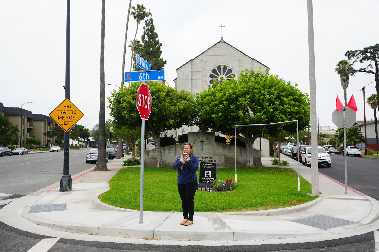 Melyssa Rivas stands at an intersection where she witnessed masked federal agents detaining a person earlier this month outside Our Lady of Perpetual Help Catholic Church in Downey, Calif., on Friday, June 20, 2025. (AP Photo/Damian Dovarganes)