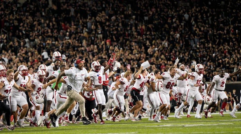 Miami players and coaches celebrate after a defensive back Yahsyn McKee intercepts the ball in the end zone during overtime of an NCAA college football game against Cincinnati, Saturday, Sept. 16, 2023, in Cincinnati. (AP Photo/Jeff Dean)
