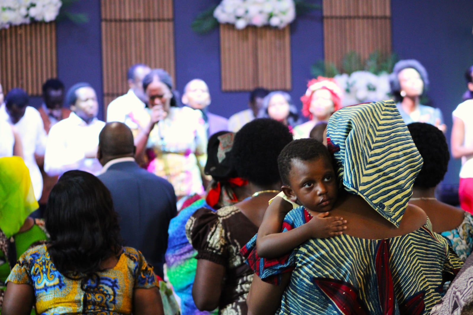 A sleepy child looks over a woman's shoulder at the Penuel Church of the Nazarene Service on Sunday, July 20. STAFF/SYDNEY DAWES