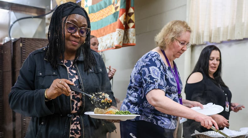 Dr. Chi Adeliyi (left), the director of East Dayton Fellowship Community Development Initiatives, scoops food on her plate during a lunch hosted by Cross Over Community Development on May 13 at Christ Evangelical Lutheran Church. BRYANT BILLING / STAFF
