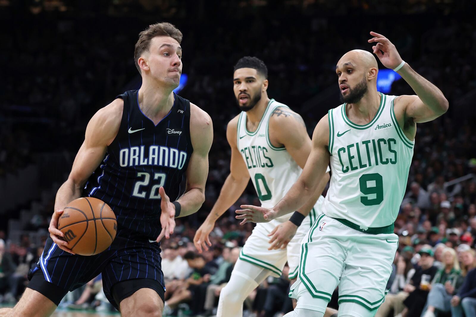 Orlando Magic's Franz Wagner (22) drives past Boston Celtics' Derrick White (9) in front of Jayson Tatum (0) during the second half in Game 1 of a first-round NBA playoff basketball series Sunday, April 20, 2025, in Boston. (AP Photo/Michael Dwyer)