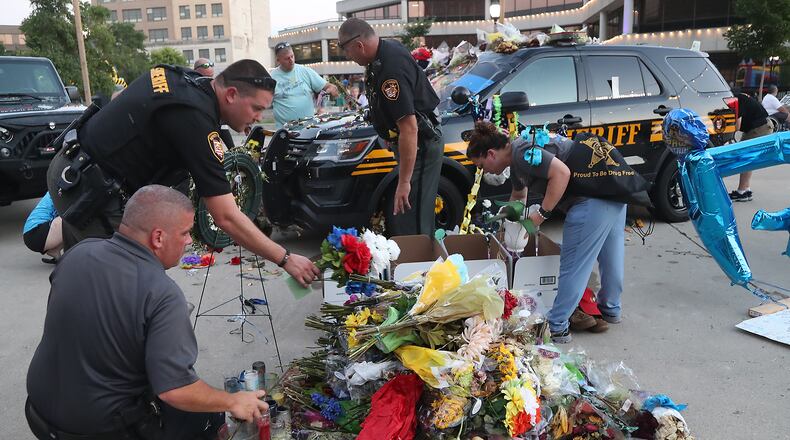 In this file photo members of the Clark County Sheriff's Office and volunteers remove and sort through the flowers and mementos that have been left on and around the Deputy Matthew Yates memorial. Springfield City Commissioners have officially declared July 24 as Deputy Matthew Yates Day annually in Springfield. BILL LACKEY/STAFF