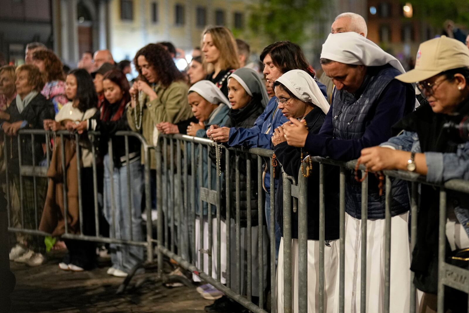 People attend a rosary prayer outside the Santa Maria Maggiore Basilica, where the late Pope Francis will be buried, in Rome, Thursday, April 24, 2025. (AP Photo/Andreea Alexandru)