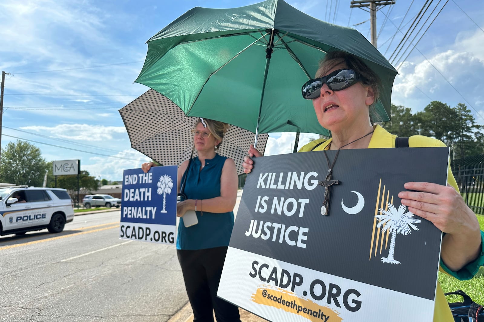 Protesters shielding themselves in the 84-degree heat await the planned execution of Stephen Stanko outside the Broad River Road Correctional Institution in Columbia, S.C., on Friday, June 13, 2025. (AP Photo/Allen G. Breed)
