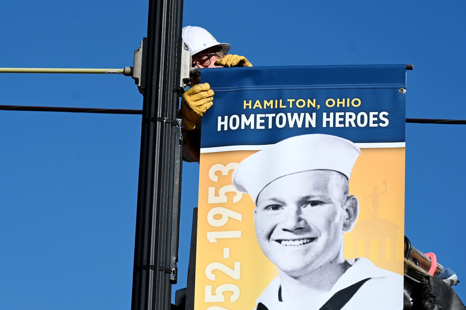 Pictured Travis Jenkins, an employee with the Hamilton Department of Infrastructure, installing on Wednesday, April 30, 2025, the Hometown Hero banner of the late Richard Underwood, the founder of Richard's Pizza. His banner is in front of the pizzeria he built in 1969 on Main Street. There will be more than 620 Hometown Hero banners installed around the city and on display until Veterans Day, Nov. 11, 2025. MICHAEL D. PITMAN/STAFF