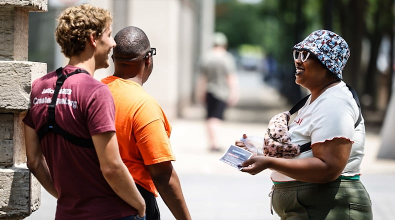 Jasmine Like (right from Dayton) talks with a representative (left) from Created Equal, a national anti-abortion organization that was in downtown Dayton with large signs on Wednesday July 19, 2023. Marcus Bedinger is the person in the middle. JIM NOELKER/STAFF.