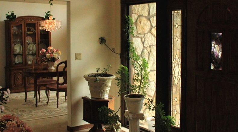 Ceramic tile covers the floor in the central front entry. To the right in the formal dining room, faceted crystal pendants add shimmering light from the chandelier centered on the ceiling.