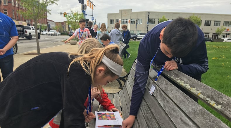 Xenia fifth-graders, from left, Nadia Lewis, Maddi Janowiecki and Cory Pham look at possible flowers to include in their adoption of a flower pot and landscape island in the downtown area as part of the city’s Bloom with Xenia program. RICHARD WILSON/STAFF