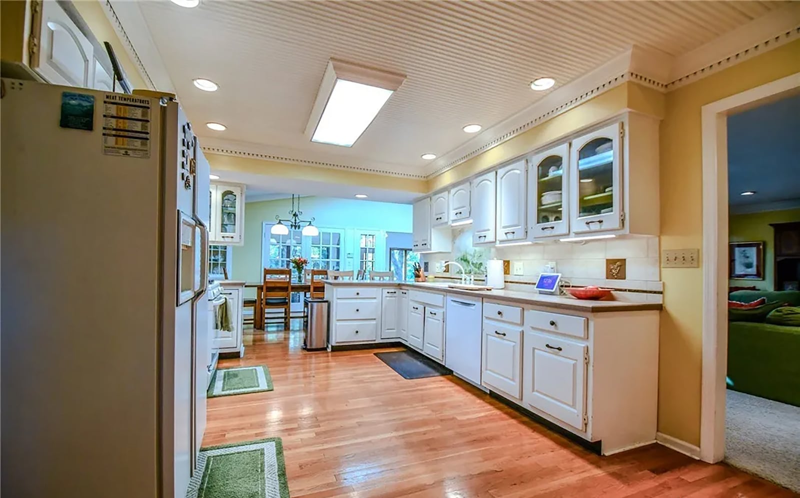 The eat in kitchen has hardwood flooring, solid surface countertops, a tile backsplash and wood cabinets. The eat in area has a skylight and a built in corner cabinet. CONTRIBUTED