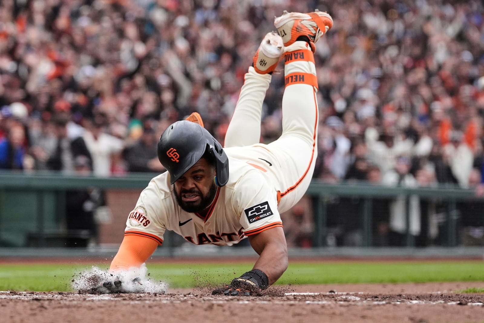 San Francisco Giants' Heliot Ramos scores the game-winning run on a throwing error Texas Rangers first baseman Jake Burger during the ninth inning of a baseball game Sunday, April 27, 2025, in San Francisco. (AP Photo/Godofredo A. Vásquez)