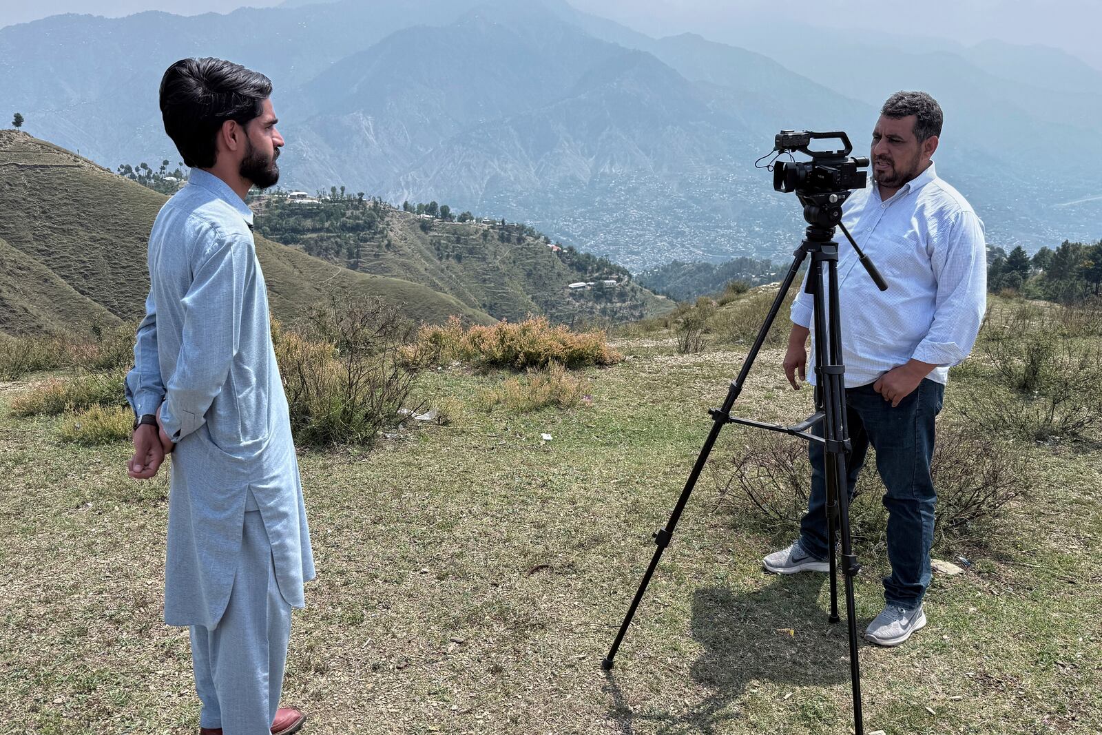 A cameraman records an interview with a villager during a government's organized trip for media to Bella Noor Shah, a mountainous village near Muzaffarabad, the capital of Pakistan administered Kashmir, Monday, May 5, 2025. (AP Photo/Muhammad Yousuf, Pool)