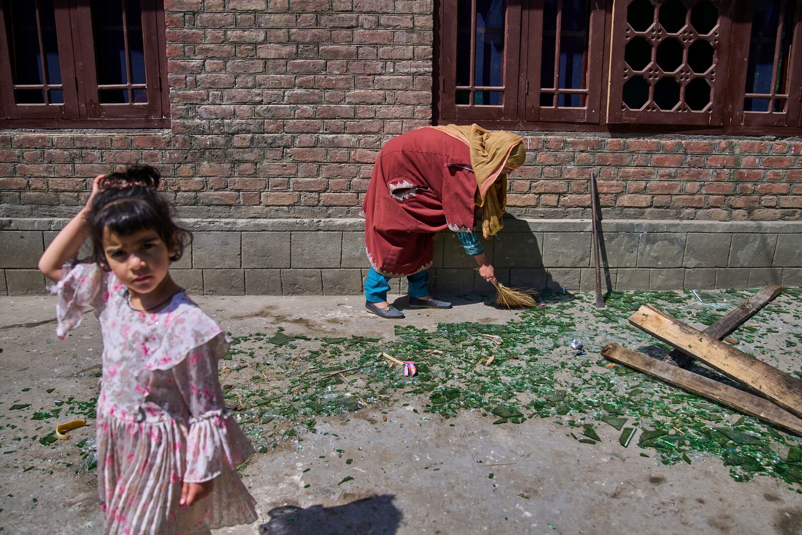 A Kashmiri woman clears shattered glass outside her home after it was damaged in a blast at the house of Asif Sheikh, who officials say is a militant and have blamed for involvement in the deadly attack on tourists in Pahalgam, at Monghama village in Tral, south of Srinagar, Indian controlled Kashmir, Friday, April 25, 2025. (AP Photo/Dar Yasin)