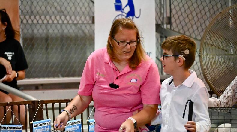 Gunner Lawson (right), a young boy who is blind and partially deaf, shows his rabbit at the Greene County Fair with the help of 4-H advisor Courtney Montgomery (left) Monday, July 28, 2025. CONTRIBUTED