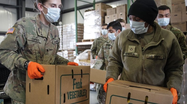 Ohio National Guard members help load food into trunks at The Foodbank at 56 Armor Place in Dayton. STAFF/JIM NOELKER