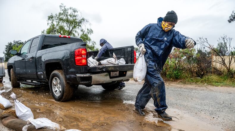 James Jones places a sandbag to prevent water from running off a property scorched in the Eaton Fire in Altadena, Calif., as the region remains under flash flood warnings on Saturday, Nov. 15, 2025. (AP Photo/Noah Berger)