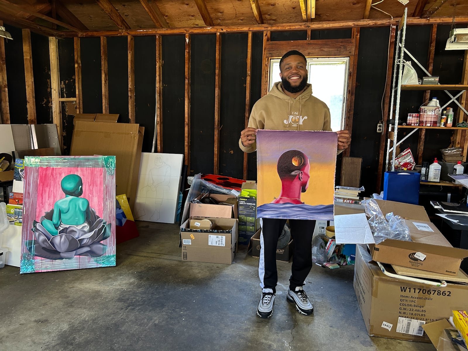 Artist Jamaal Durr in his studio, holding up work from a recent gallery show at Loma Galleries in Atlanta.