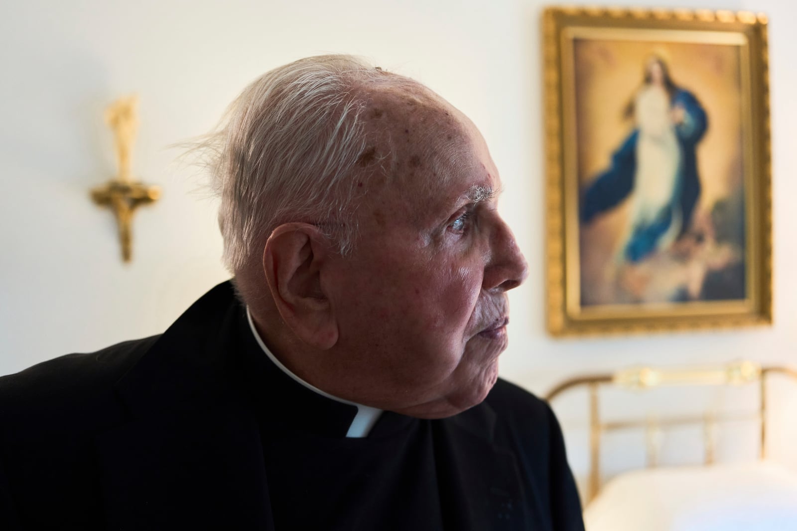 The Rev. James Kelly looks out his apartment window in the Normandy Farms Estates retirement community in Blue Bell, Pa., on Wednesday, June 18, 2025. (AP Photo/Luis Andres Henao)