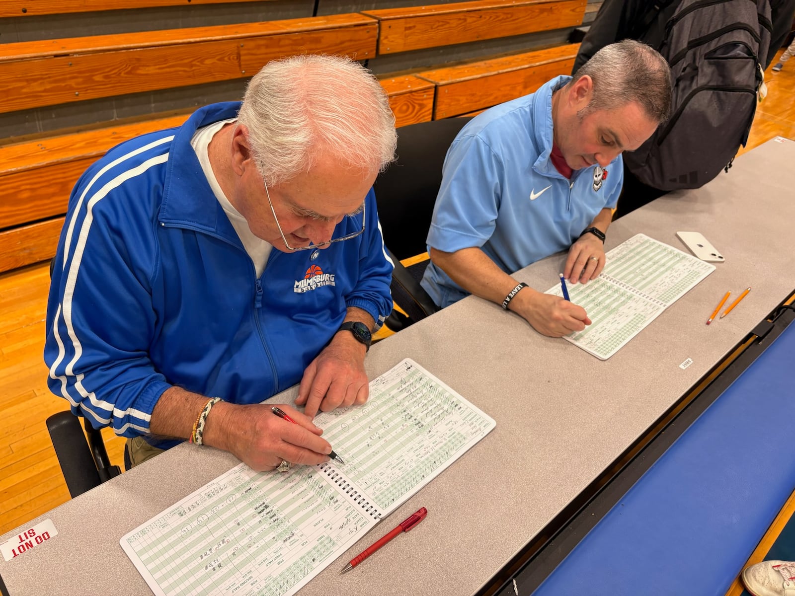 Miamisburg High School boys basketball scorekeeper Ron Anslinger and Kings scorekeeper Phil Poggie tally the scorebook after their game on Feb. 17, 2026. Anslinger has kept the book for the boys basketball program for more than 55 years. TOM ARCHDEACON / CONTRIBUTED PHOTO