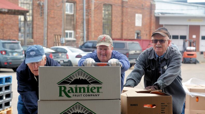 Volunteers bring fruit into the work area as volunteers prepare baskets for the 2015 Christmas Basket project by Tipp City Needy Basket. CONTRIBUTED