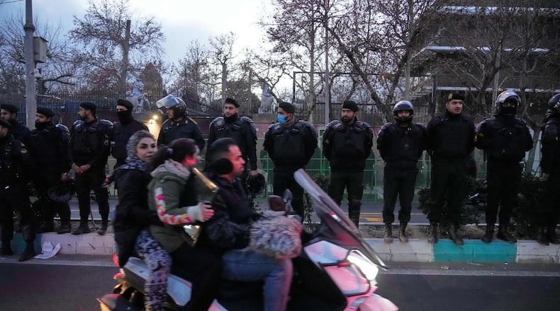 Policemen protect the British Embassy during a protest by hardline supporters of the Iranian government, as people ride on their motorbike in Tehran, Iran, Wednesday, Jan. 14, 2026. (AP Photo/Vahid Salemi)